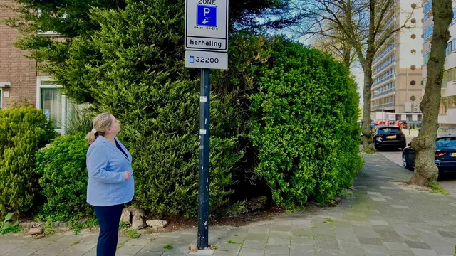 Een vrouw kijkt naar een parkeerbord met zonenummer in een woonwijk